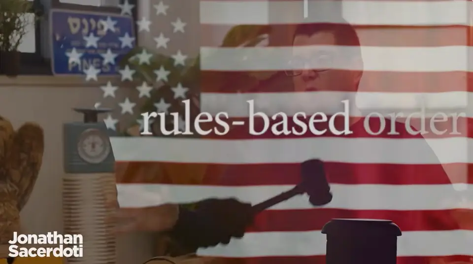 Danny Orbach on Jonathan Sacerdoti's show, overlaid with a US flag and 'rules-based order'