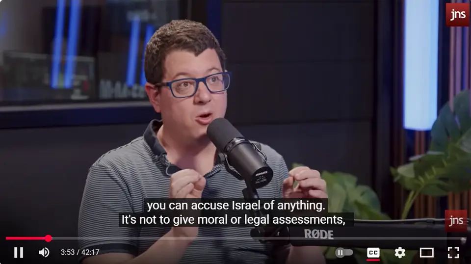 Danny Orbach speaking into a microphone in a JNS TV interview