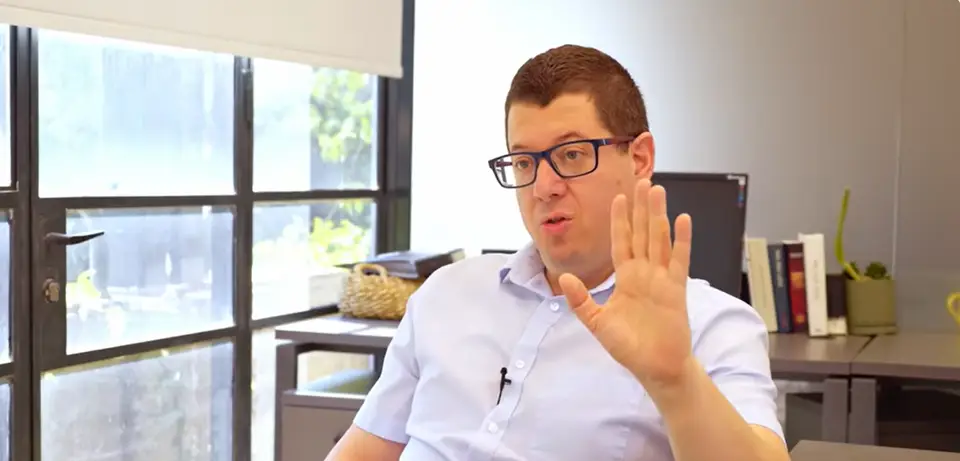 דני אורבך מסביר בתנועת יד במהלך ראיון במשרד